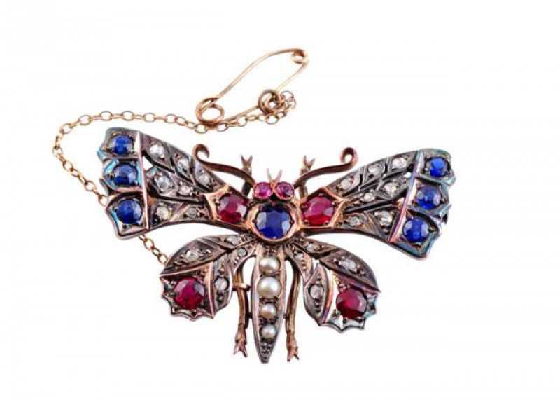 A Victorian diamond, sapphire, ruby and seed pearl butterfly brooch, the realistic design set to the centre of the body with a round mixed cut claw set sapphire, set to the top of four graduating seed pearls, between two round mixed cut claw set rubies to