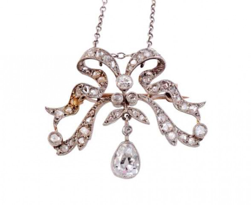A diamond pendant, circa 1890-1900, designed as a stylised bow, suspending on an articulated link an oval mixed cut collet set diamond and small diamond highlight to the centre, the entirety of the bow set with graduating old cut and old brilliant cut dia