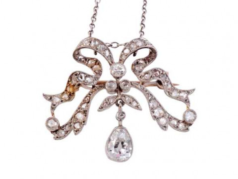 A diamond pendant, circa 1890-1900, designed as a stylised bow, suspending...