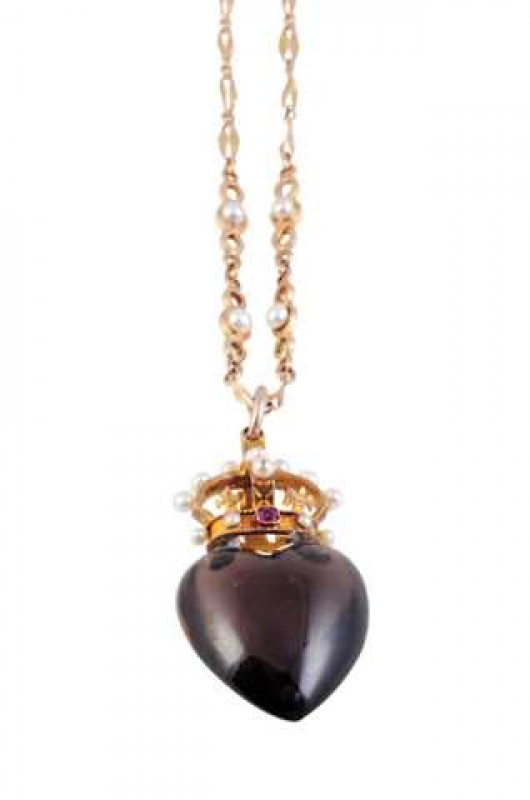 A smoky quartz, seed pearl and garnet pendant, the large heart shaped cut smoky quartz to the bottom of a mount designed as a crown, set throughout with seventeen graduating seed pearls and two square cut garnet highlights in collet settings, suspending f