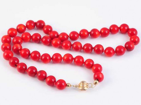 A red coral necklace, the forty six uniform coral beads threaded onto...