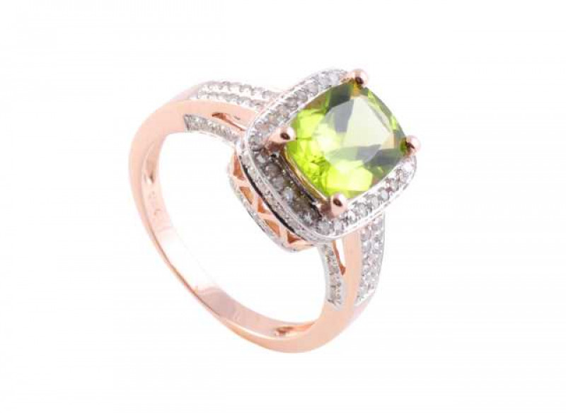 A peridot and diamond ring, the central oval cut peridot four claw set to the centre of a square mount within a bezel of thirty brilliant cut claw set diamonds to the top mount, the top side of the mount set with brilliant cut diamond highlights, all set 