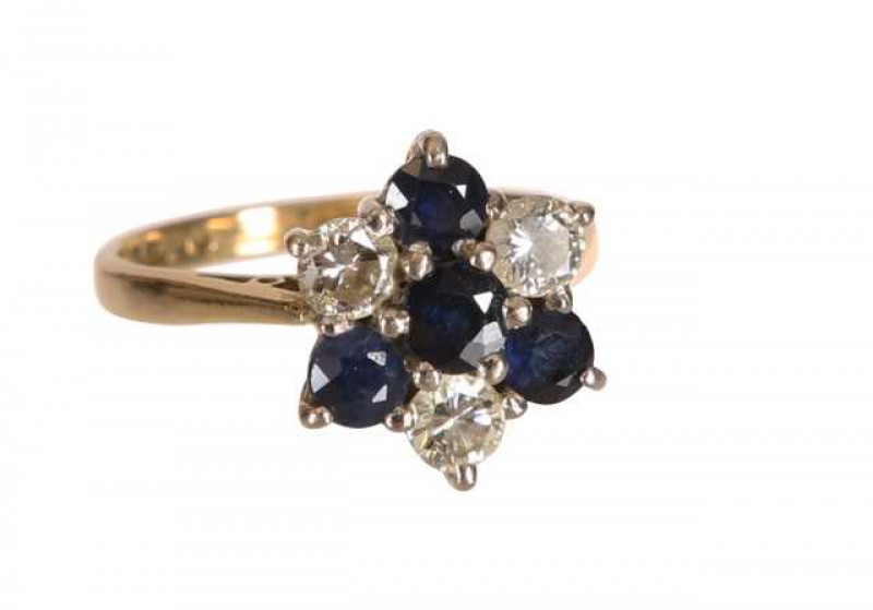A sapphire and diamond ring, the central round cut sapphire six claw set, slightly raised within a surround of three round cut claw set sapphires, alternately spaced with three brilliant cut claw set diamonds, all set in a pierced detail mount between tap