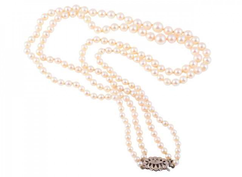 A cultured pearl necklace, the double strand of one-hundred and forty-three uniform cultured pearls strung simply onto an integral tongue clasp set with a further nine cultured pearls to form a flowerhead shape. Clasp stamped 375. Length approx. 20.5cm. W