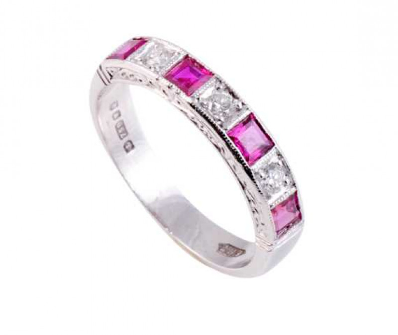 A ruby and diamond ring, the four square cut collet set rubies alternately set with three brilliant cut claw set diamonds, all set in open mounts with engraved detailing to the side. Stamped 750. Ring size N1/2