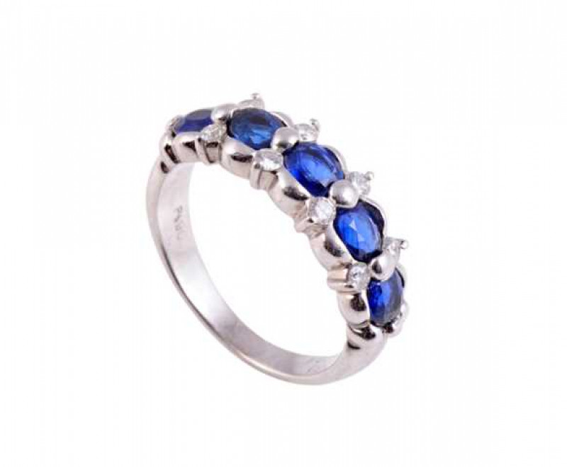 A sapphire and diamond ring, the five claw set oval mixed cut sapphires alternately spaced with four clusters of two brilliant cut claw set diamond highlights, all set in a moulded detail mount on a plain band. Stamped PT. Ring size K.