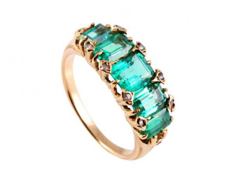 A five stone emerald ring, the central square cut emerald claw set between...