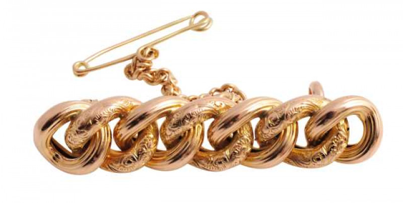 A Victorian brooch, designed as seven interlocking circles of alternate engraved and textured detailing, on brooch pin fitting with safety chain. Weight approx. 5.4gms. Length approx. 4cm.