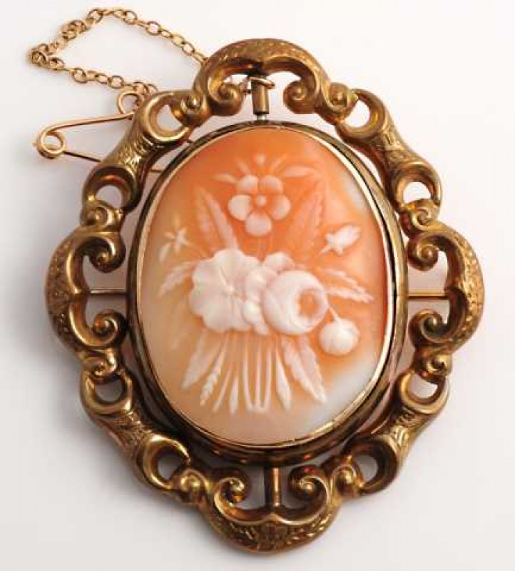 An mid Victorian cameo brooch, the oval cameo depicting a floral scene, collet set in a heavy mount engraved to the edge 'In memory of I.J Dixon. From B Reed to J. Hunter', the mount revolving within an elaborate outer mount of moulded links and engraved 