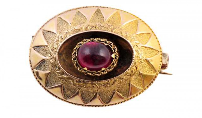 A mid Victorian garnet brooch, set to the centre with an oval cabochon cut collet set garnet, set within a moulded detail mount set throughout with interwoven designed rope work detailing. Brooch pin fitting. Weight approx. 4.3gms.