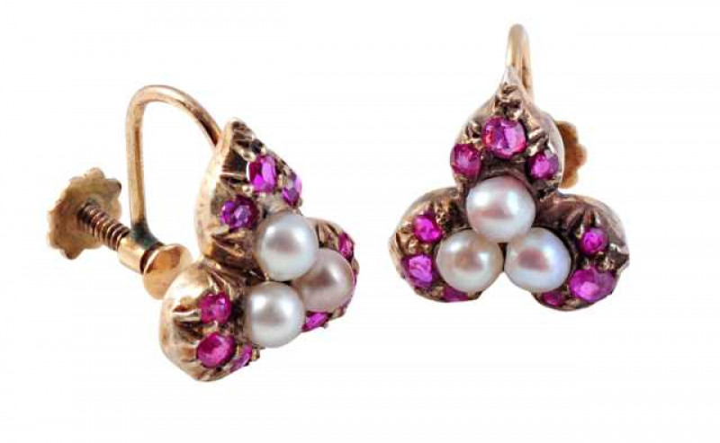 A pair of pearl and ruby earrings, the three natural pearls set as a cluster to the centre of three leaf shaped mounts, each set with three old mixed cut claw set ruby highlights, all set in an open mount to the bottom of screw back fittings. Weight of on