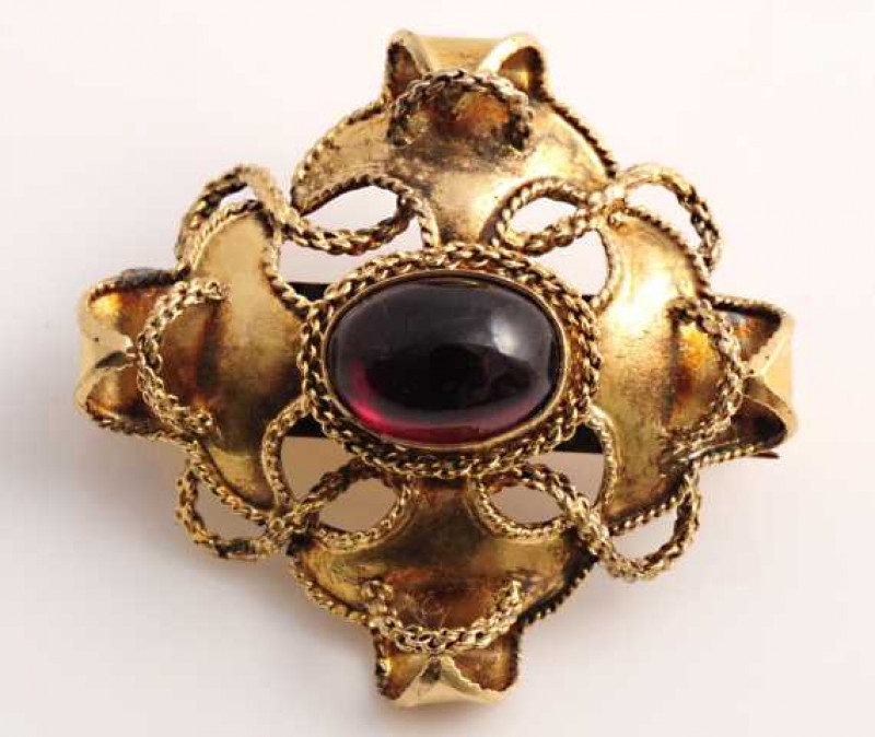 A mid Victorian garnet hair locket mourning brooch, set to the centre with an oval cabochon cut claw set garnet, within a concave mount with delicate rope work detailing, in turn within a textured and subtly engraved mount with brooch pin fitting. Glass h