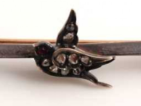 A late Victorian diamond and ruby brooch, modelled as a bird, simply set...