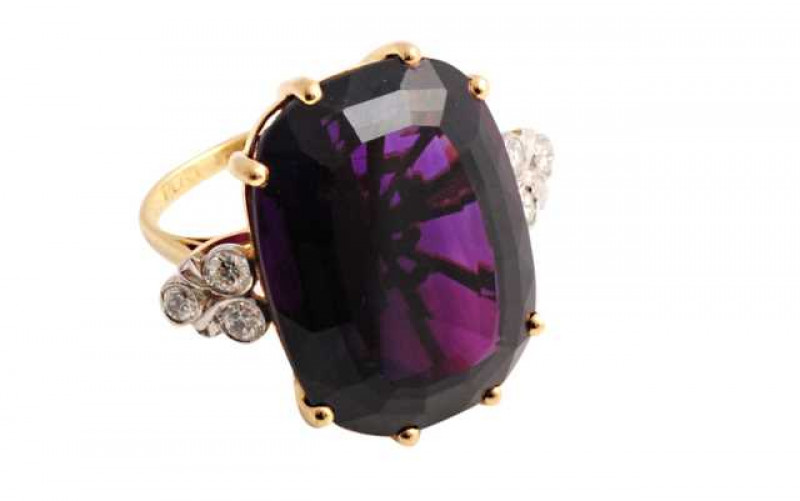 An amethyst and diamond ring, the large mixed oval cut amethyst eight claw set between three brilliant cut collet set diamonds to each shoulder, all set in an open mount between tapering shoulders on a plain band. Stamped 18CT PLAT. Ring size N1/2
