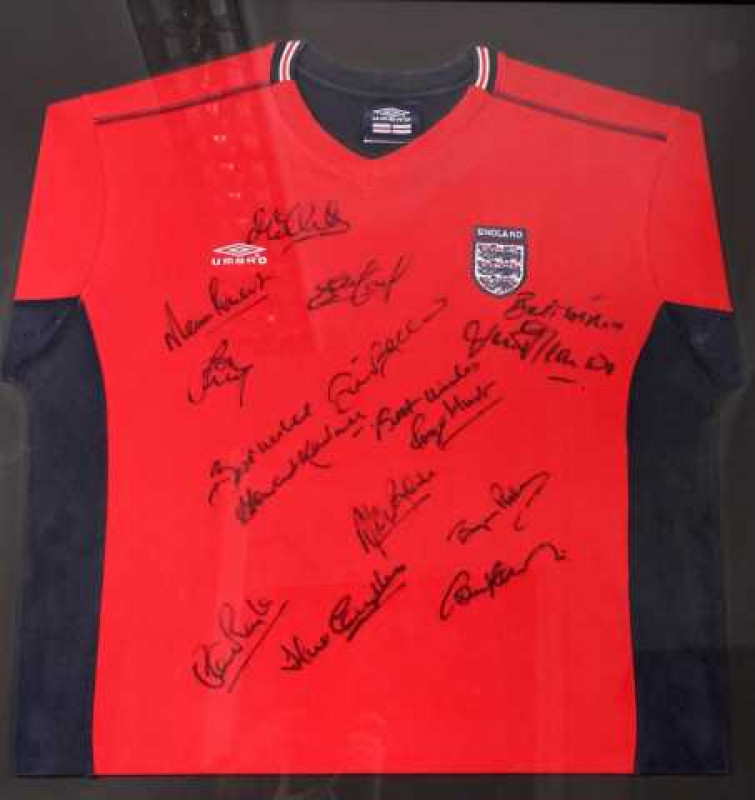 A signed replica England football shirt, signatures include Roger Hunt, Howard Kendall and Bryan Robson, framed with some signatures verso. Overall 79cm by 79cm