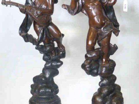 Pair of bronze musical putti each on naturalistic ground playing violin...