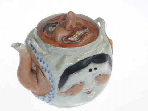 Oriental novelty teapot modelled with four faces to sides and a further...