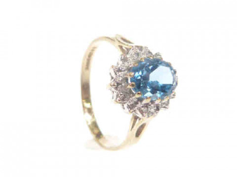 9ct gold ring set with an oval blue topaz within a surround of diamonds,...