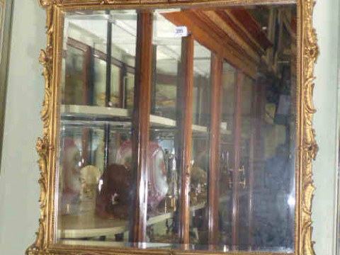 Gilt framed bevelled wall mirror with child musician crest, 81cm x 73cm