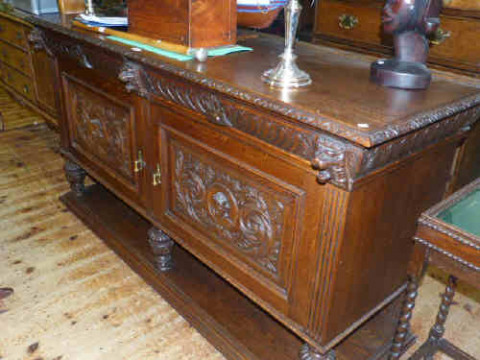 Heavily carved oak sideboard having two frieze drawers above cupboard...
