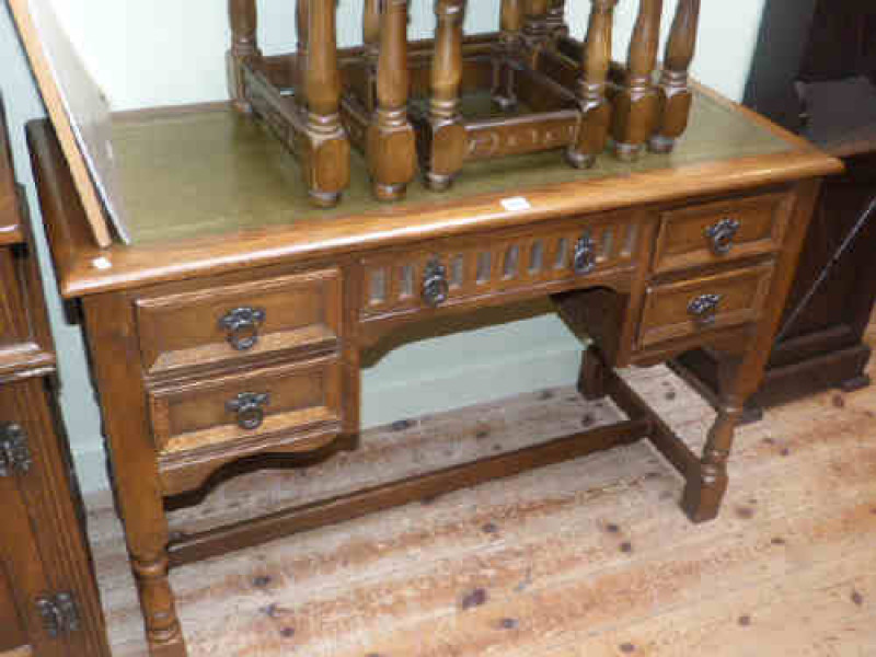 Oak kneehole desk raised on turned legs with cross stretcher having green leather top
