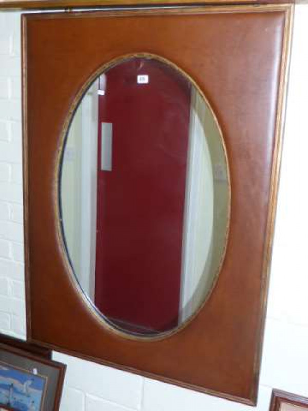 Oval wall mirror in cushioned frame