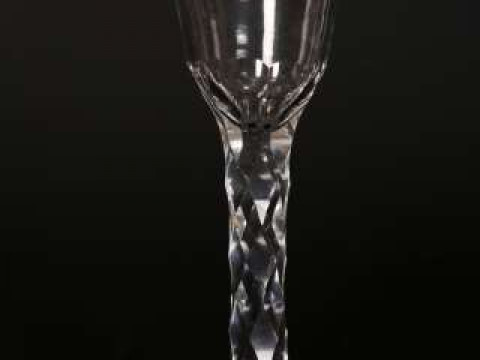 A facet stem wine glass, c.1780, the base of the round funnel bowl crested...