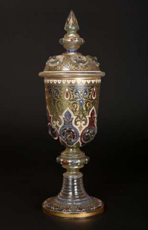A large Bohemian glass covered goblet, the cover and body moulded with prunts, stained, gilded and engraved with scrolling foliage and alternating red and blue ground panels, raised on a stepped circular foot rising to a ring moulded stem. 41cm