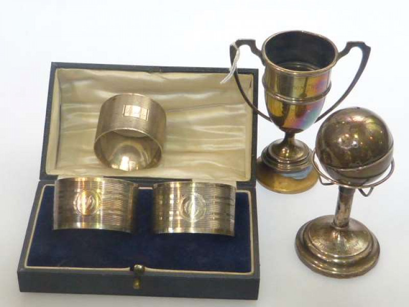 Three silver napkin rings, small silver trophy cup and silver golfing trophy (5)