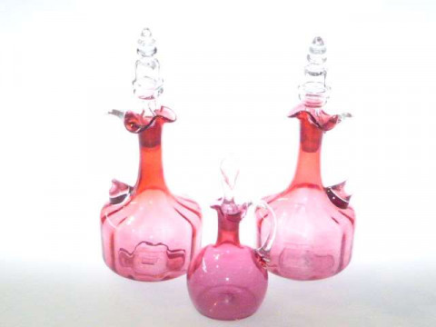 Three cranberry glass decanters