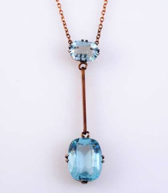 A BLUE TOPAZ PENDANT c.1890 The cushion cut topaz four double claw set in a simple open mount suspending on an articulated link to the bottom of a rectangular flat edge bar, in turn suspending on an articulated link from an oval cut four double claw set t