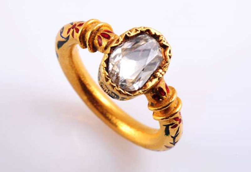 A DIAMOND AND ENAMEL RING c.1840-50 The oval table cut diamond collet set in texture metal mount set to the sides and reverse with floral detail enamelling in green, blue and red, set to the top a heavy rounded band with moulded detailing on the shoulders
