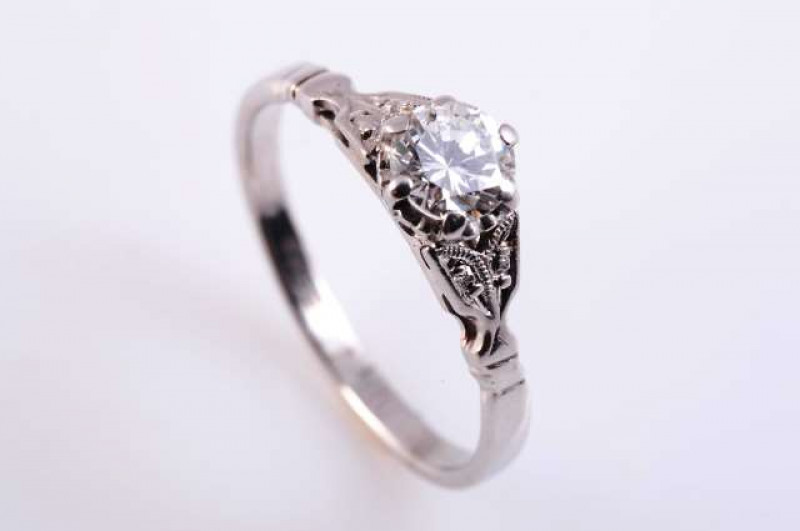 A DIAMOND RING c.1910-20 The brilliant cut diamond six claw set in an open pierced detail mount between open moulded leaf shaped shoulders on a plain band. Stamped 18.  Ring size M. Weight approximately 2.3gms.