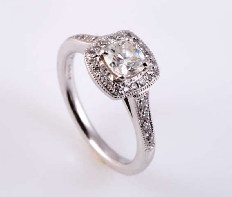 A DIAMOND AND PLATINUM RING The cushion cut diamond four claw set within a bezel of twenty brilliant cut claw set diamond highlights in an open mount between open shoulders each set with five graduating brilliant cut diamond highlights, on a plain band. S
