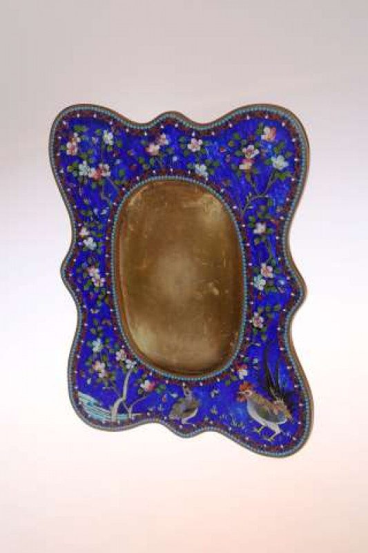 A CHINESE CLOISONNE ENAMEL PHOTOGRAPH FRAME Of shaped rectangular form with easel back, decorated with chickens and blossoming boughs against a cobalt ground. 24cm by 19cm