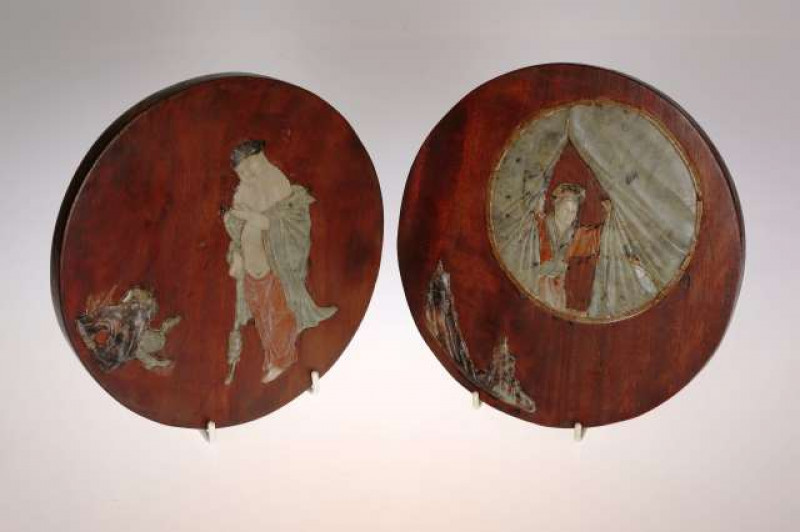AN INTERESTING PAIR OF CHINESE HARDWOOD AND JADEITE PANELS The first plaque applied with jadeite to depict a woman looking through drawn-back curtains, with a mountainous vignette applied below; the second plaque with a man dressed in robes. 20cm