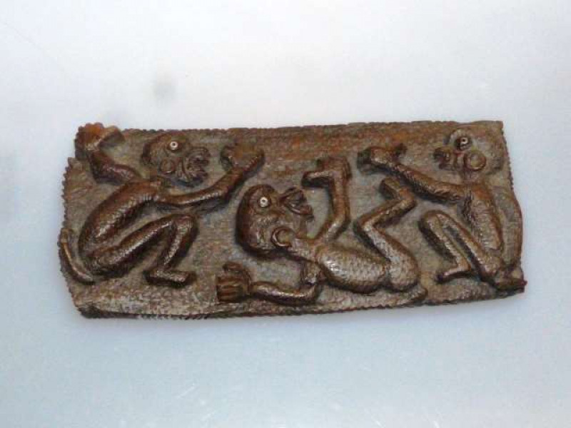 AN UNUSUAL CARVING Possibly tribal, the board carved with three figures with inset eyes. 30cm by 13cm