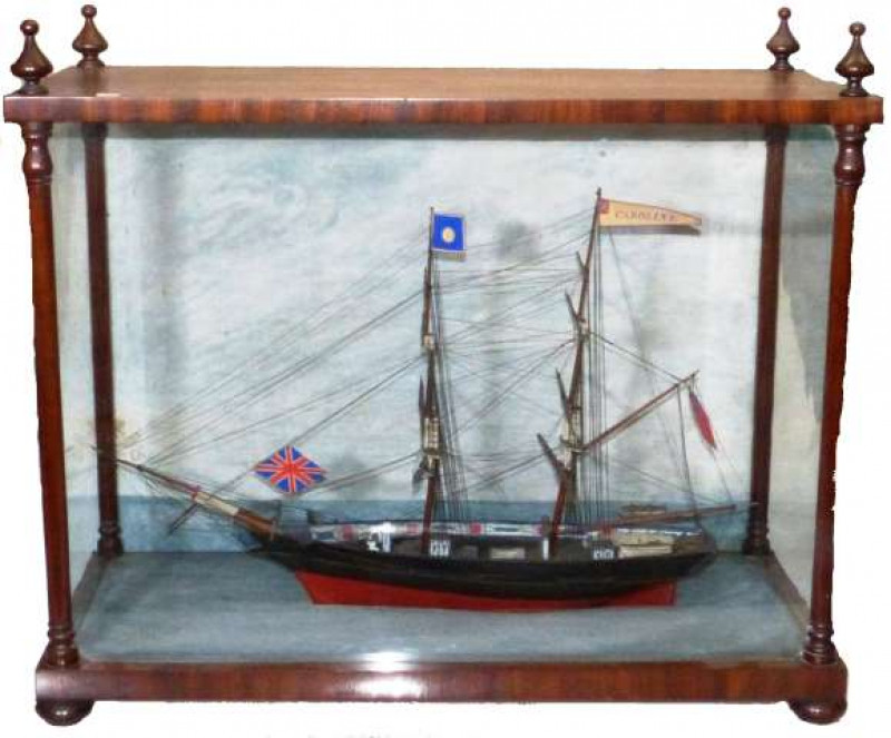 A GOOD VICTORIAN MAHOGANY CASED MODEL SHIP Depicting the two-masted ship 'Caroline', the mahogany case with turned finials and columns, raised on flattened bun feet. 64cm by 75cm by 34.5cm