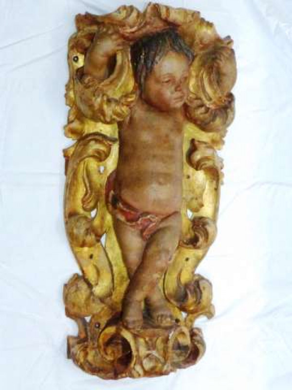 A POLYCHROME AND GILT-COMPOSITION CARVING Possibly Italian A standing putto within a surround of scrolls. 92cm high