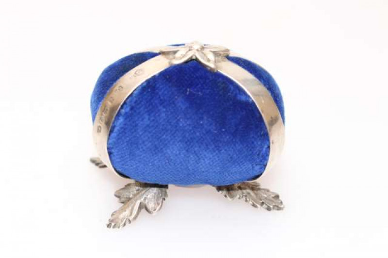 A SILVER-MOUNTED PIN CUSHION, Martin, Hall & Co, Sheffield 1877, raised on four feet cast as acanthus leaves.
