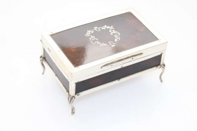 A GEORGE V SILVER AND TORTOISESHELL JEWEL BOX, London 1919, rectangular, the hinged cover centred by a silver inlaid foliate cartouche, raised on leaf-capped cabriole legs, of particularly good quality. 10.5cm by 7cm