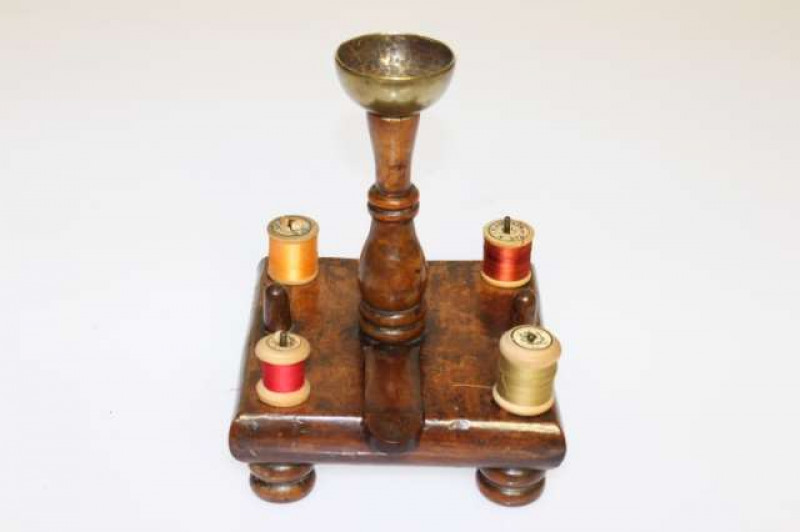A WALNUT SEWING STAND, 18th Century, the square platform with four bobbin holders and two thimble holders, raised on turned feet. 20cm high
