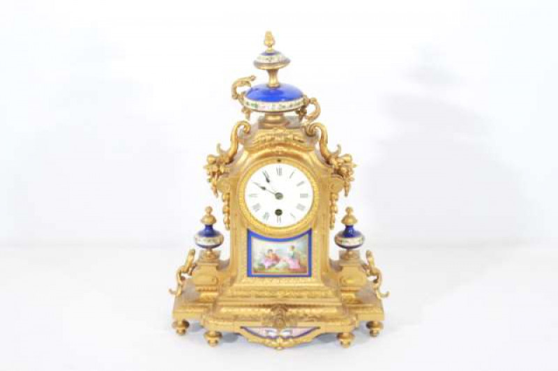 A FRENCH 19TH CENTURY GILT-METAL AND PORCELAIN MANTEL CLOCK, the urn-topped case cast with scrolls and foliage, inset with a porcelain panel painted with a courting couple, the white enamel dial with Roman numerals. 38cm high