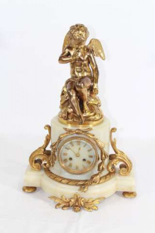 AN ORMOLU AND MARBLE STRIKING MANTEL CLOCK, c.1890, surmounted by a seated winged cherub, fluted marble central column flanked by scroll mounts, the dial with applied Roman numerals, twin barrel movement striking on a bell, signed Charpentier A Paris, bac