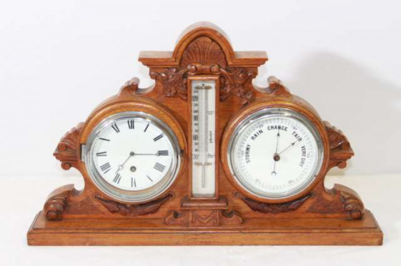 A 19TH CENTURY CARVED OAK DESK WEATHER STATION, inset with a clock, thermometer and barometer. 53cm wide