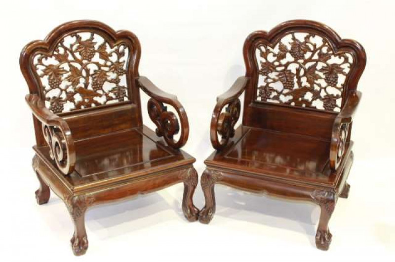 A PAIR OF CHINESE HARDWOOD ARMCHAIRS, each with arched top rail above a fret carved back of fruiting vine, issuing scrolling arms, raised on cabriole legs terminating in ball and claw feet.