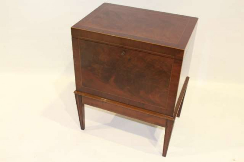 AN INLAID MAHOGANY CELLARETTE, the hinged rectangular top opening to reveal an interior with dividers, the case with crossbanding and barber's pole stringing, raised on an integral stand with moulded square-section tapering legs. 65cm by 53cm by 38cm