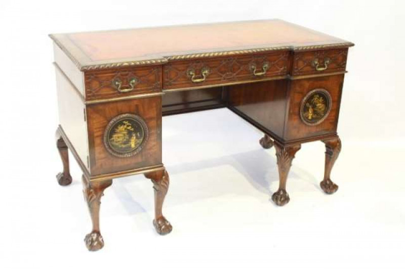 A CHIPPENDALE STYLE CHINOISERIE DECORATED MAHOGANY DESK, the inverted breakfront leather-inset top with gadrooned edge over three frieze drawers with blind-fretwork carved fronts, above two pedestals with cupboard doors centred by chinoiserie panels, rais