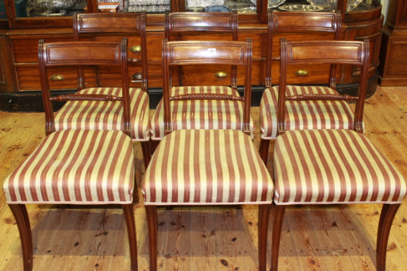 A SET OF SIX REGENCY MAHOGANY DINING CHAIRS, each with moulded tablet back above a twist-carved rail, the stuffed over seat raised on moulded sabre legs.