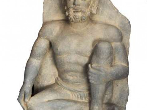A STONE CARVING OF A SEATED BEARDED MAN, sitting cross legged. 52.5cm...